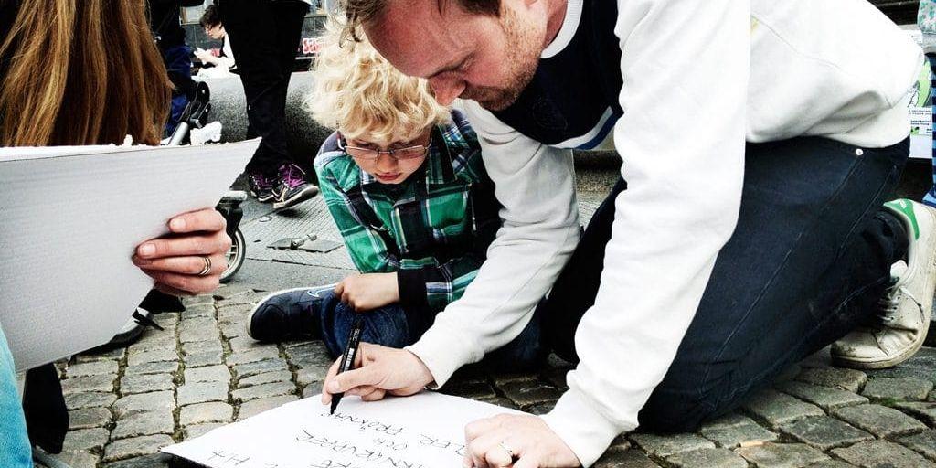 Per Nilsson med sonen Albin tillverkar ett plakat.